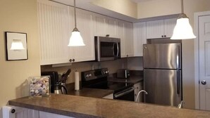 Una cocina moderna con gabinetes blancos, electrodomésticos de acero inoxidable e iluminación colgante.