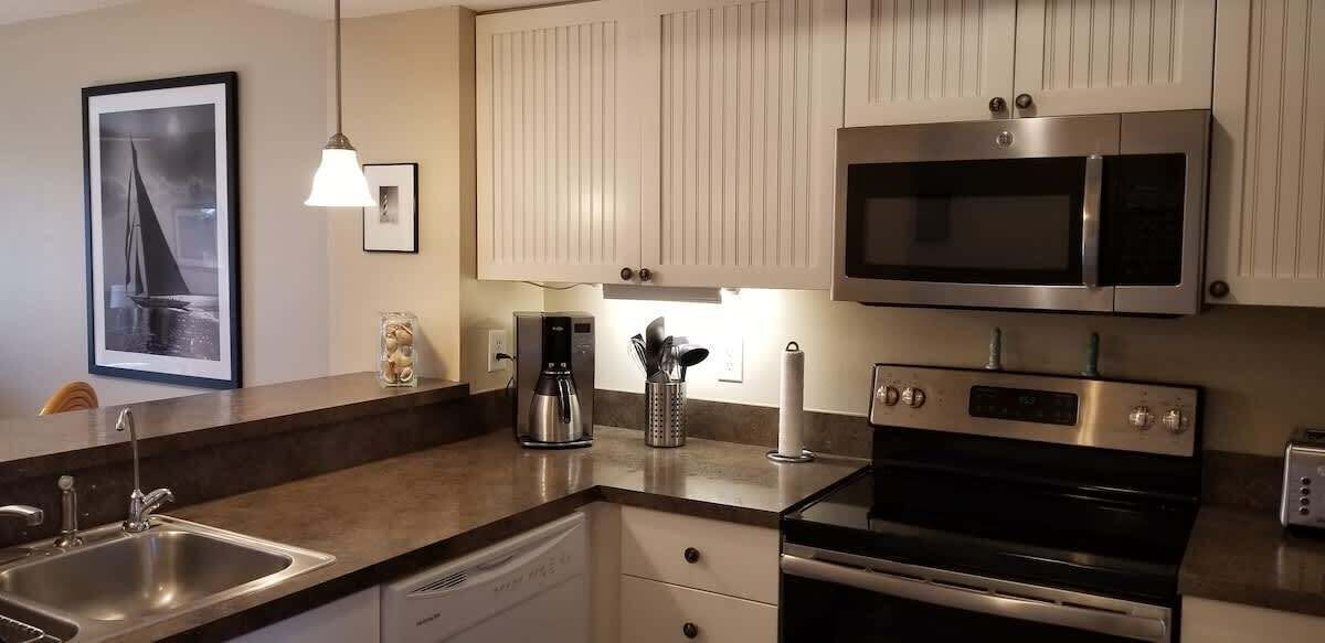 Eine moderne Küche mit Edelstahlgeräten, einer Kaffeemaschine und einem gerahmten Bild an der Wand.