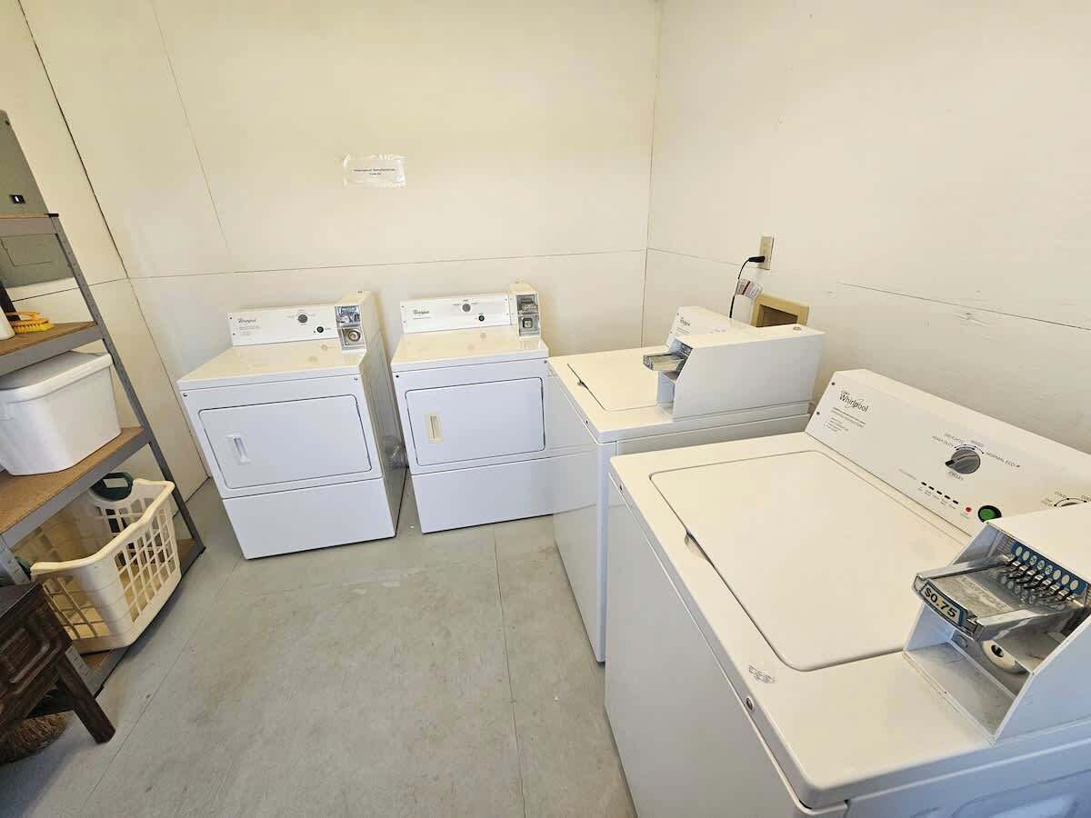 A laundry room with two front-loading washers and a stacked dryer.