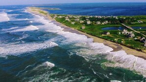 An aerial view of a coastal area with a beach, grassy areas, and a few buildings. - Have it all! The perfect Nantucket getaway for stunning ocean views and beaches! (Nantucket)