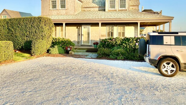 A two-story house with a covered porch, a driveway, and a parked SUV. - Have it all! The perfect Nantucket getaway for stunning ocean views and beaches! (Nantucket)