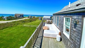 A wooden deck with outdoor seating, a view of the ocean, and a clear sky. - Have it all! The perfect Nantucket getaway for stunning ocean views and beaches! (Nantucket)
