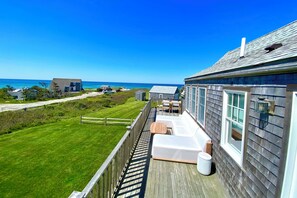 A wooden deck with outdoor seating, a view of the ocean, and a clear sky. - Have it all! The perfect Nantucket getaway for stunning ocean views and beaches! (Nantucket)