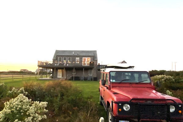 A red vehicle parked in front of a house with a balcony. - Have it all! The perfect Nantucket getaway for stunning ocean views and beaches! (Nantucket)