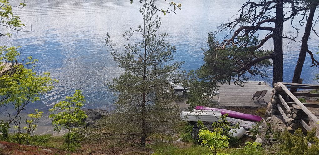 Un muelle con un área de estar techada, una canoa y un kayak junto a un lago tranquilo.