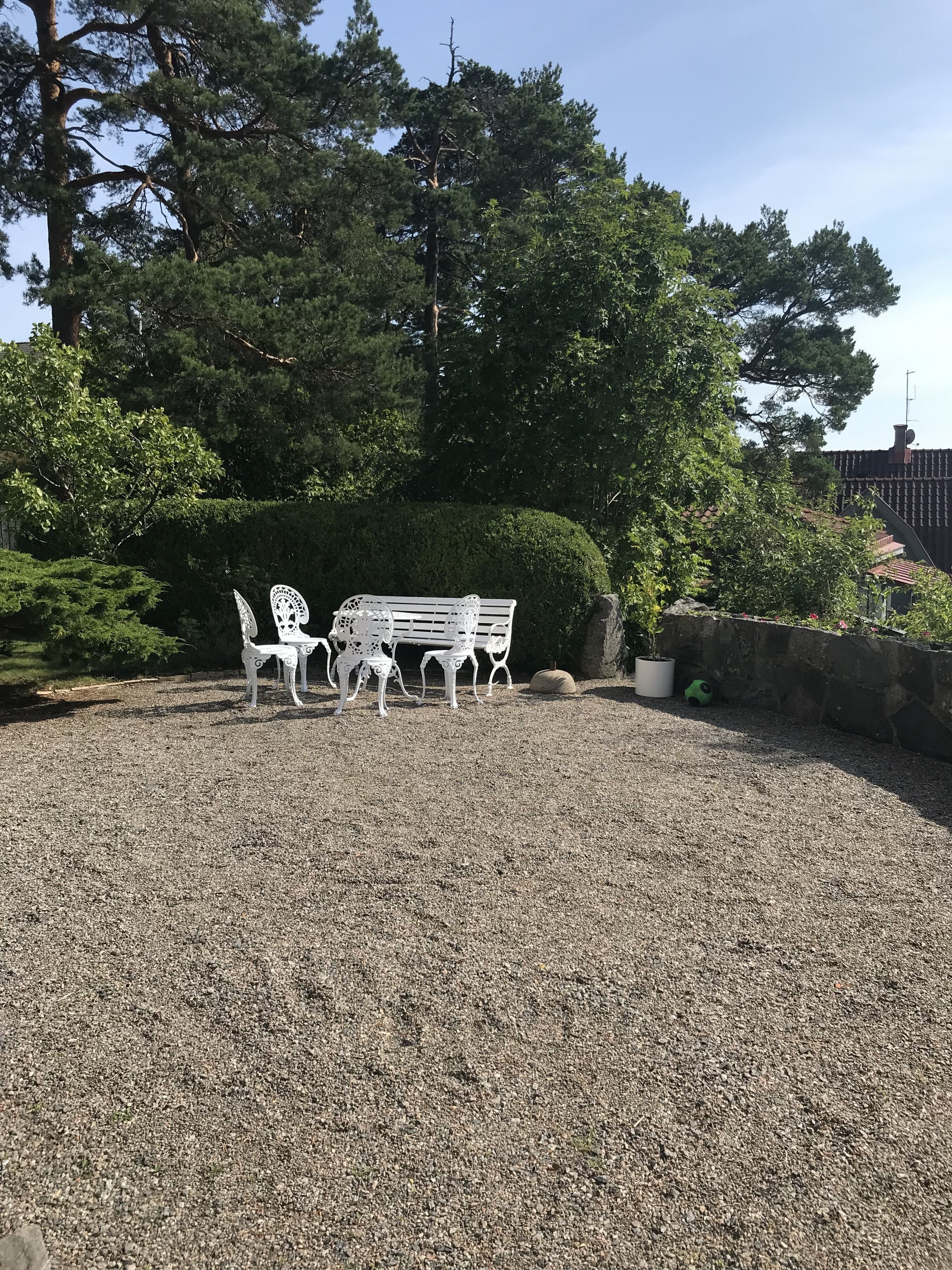 A gravel patio with a white bench and table set.