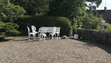 A gravel patio with a white bench and table set.