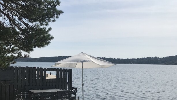 Een houten terras met een tafel, stoelen, een parasol en een loungestoel.