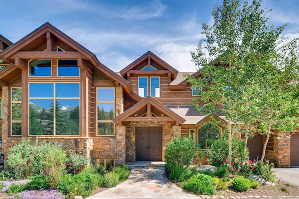 A multi-story log cabin with stone accents, large windows, and a stone entrance.
