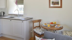 A kitchen with a sink, a window, and a dining area with a table set for breakfast.