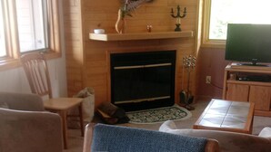 Una sala de estar con chimenea, televisor y una mesa de comedor con tres vasos de vidrio.