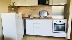 A compact kitchen with a refrigerator, microwave, toaster, sink, and oven. - Bright apartment T3 ideally located for a holiday by the sea (Saint-Cyprien)