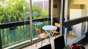 A balcony with a glass door, a small round table, and two chairs. - Bright apartment T3 ideally located for a holiday by the sea (Saint-Cyprien)