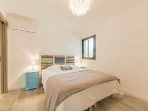 Ein Schlafzimmer mit Bett, Nachttisch, Fenster und Deckenleuchte.