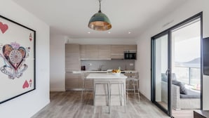 A modern kitchen with a dining area, a large window, and a mounted television. - Palazzu 36 - Château by Interhome (Porto Vecchio)