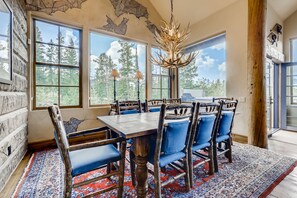 Enjoy meals in this cozy dining area with a large table and comfortable chairs, surrounded by a beautiful view.