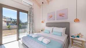 Ein Schlafzimmer mit einem großen Bett, einem Nachttisch, einer Lampe und Blick ins Freie.