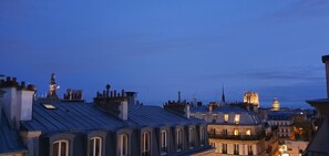Une vue sur une ville au crépuscule, avec des bâtiments historiques et une tour imposante.