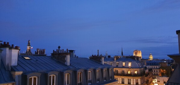 A cityscape at dusk with historic buildings and a prominent tower.