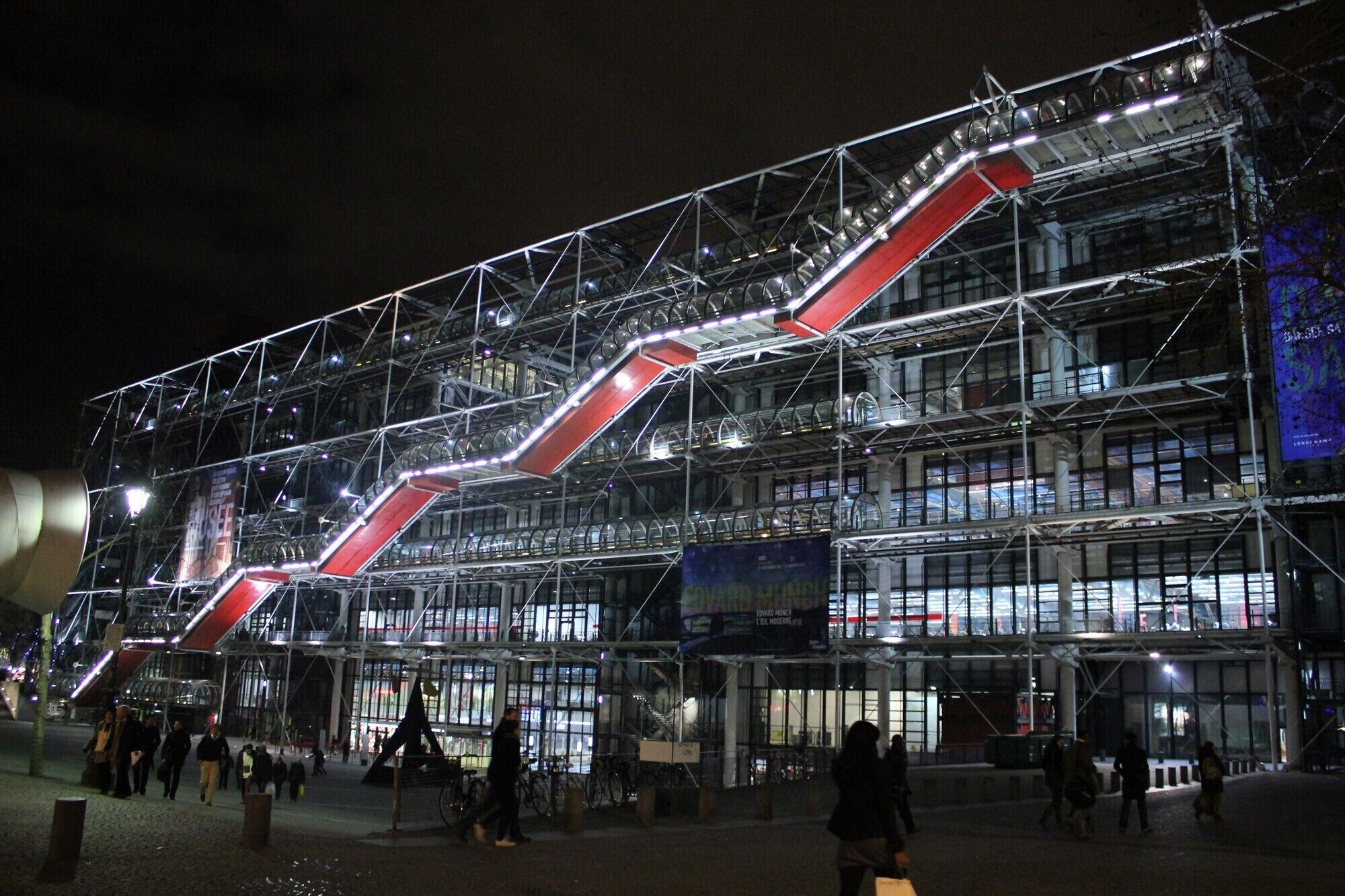 A modern building with a glass facade and a prominent red structure.