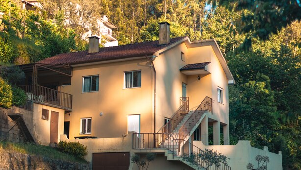 Ein zweistöckiges Haus mit Balkon, Treppe und Garage.