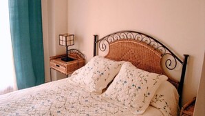 A bed with a floral quilt, a bedside table with a lamp, and a wicker basket. - FIRST LINE BEACH LUXURY APARTMENT. SEA VIEWS (Ayamonte)