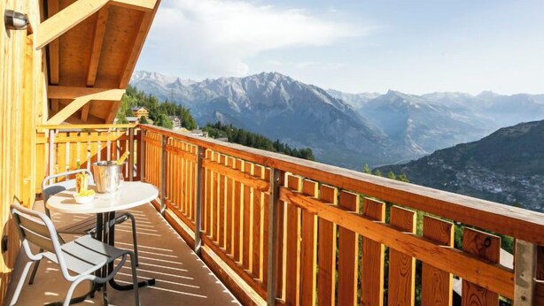 A wooden balcony with a table and chairs, overlooking a mountainous landscape. - T-Resort La Tzoumaz 2p4 vue vallée by Interhome (La Tzoumaz)
