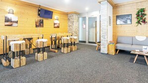 A cozy room with wooden walls, a grey carpet, a grey sofa, a small table with books, and a TV mounted on the wall. - T-Resort La Tzoumaz 2p4 vue vallée by Interhome (La Tzoumaz)