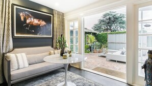 Un salon moderne avec un canapé, une table ronde et un grand tableau encadré représentant un cheval.