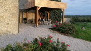 Ein Steinhaus mit einer Holzpergola und einer Kiesterrasse.