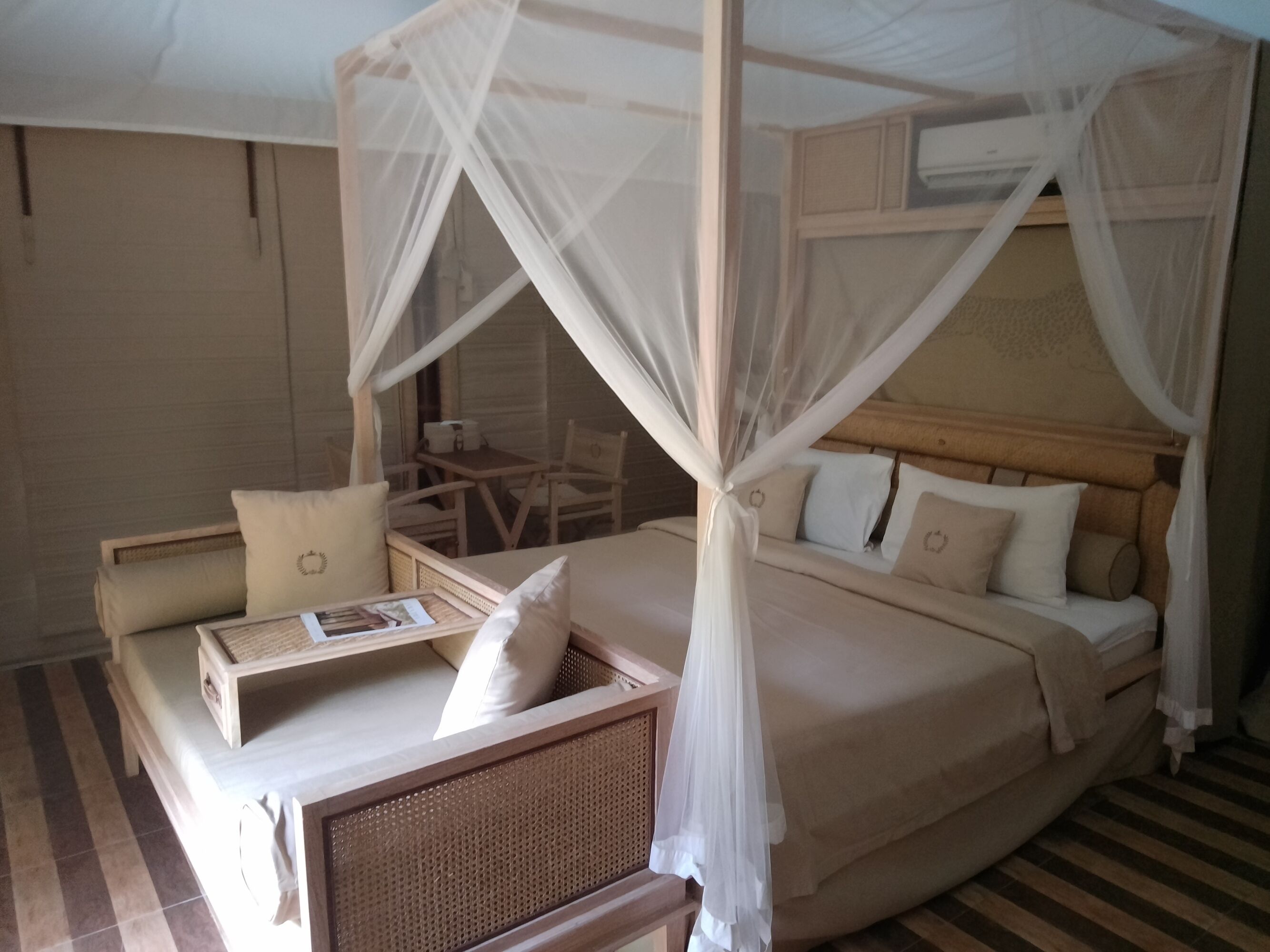 A room with a bed, a daybed, a small table, and a chair.