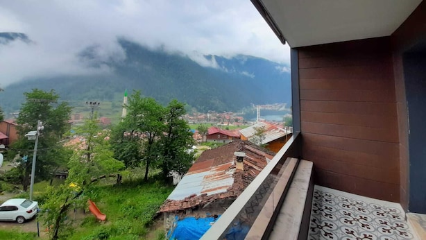 Un balcone con vista su una città, montagne e un cielo nuvoloso.