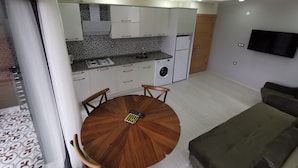 Un ambiente compatto con angolo cottura, zona pranzo e TV a parete.