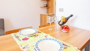 Una mesa de comedor dispuesta con platos, cubiertos y un tazón de fresas.