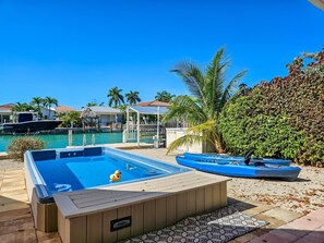 A pool area with a hot tub, a lounge chair, and a small boat. - Welcome to A Taste of Vitamin Sea – Your Key Colony Beach Escape! (Key Colony Beach)