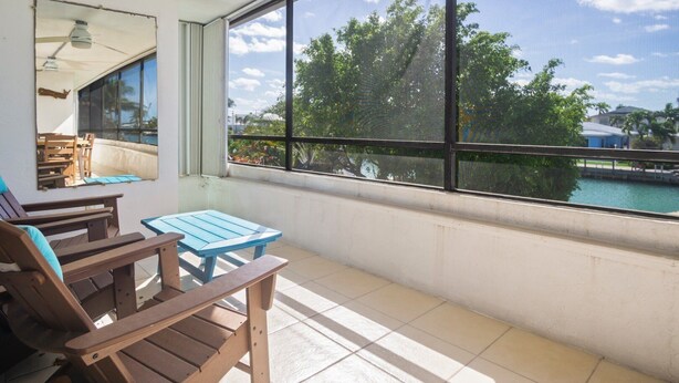 Un balcone con vista su un corpo d'acqua, un tavolo e delle sedie.