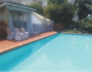 Piscina com espreguiçadeiras e área coberta.