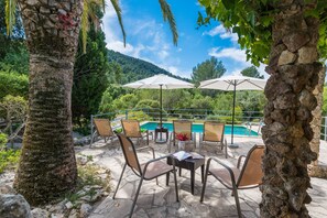 An outdoor seating area with stone tables and chairs, a pool, and umbrellas. - CAN COMPANY - Villa with private pool in Campanet. Free WiFi (Campanet)