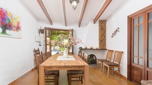 A dining area with a wooden table, chairs, and a vase of flowers. There is a stone wall and a wooden door in the background. - CAN COMPANY - Villa with private pool in Campanet. Free WiFi (Campanet)