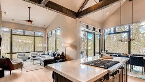 Una cocina moderna con una isla grande, electrodomésticos integrados y amplios ventanales con vistas al exterior.