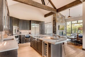 A modern kitchen with a large island, built-in appliances, and a stone accent wall.