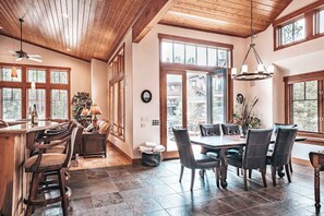 Une salle à manger spacieuse avec une grande table et des chaises, des poutres en bois au plafond et de grandes fenêtres.