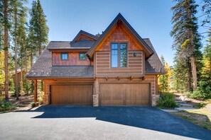 A two-story house with a garage, surrounded by trees.