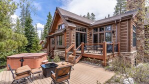 Una cabaña de madera con terraza, jacuzzi y mobiliario exterior.