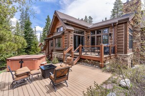 Une cabane en rondins dotée d’une terrasse, d’un bain à remous et de coins salon extérieurs.