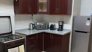 A kitchen with dark wooden cabinets, a stainless steel refrigerator, a gas stove, a toaster, and a coffee maker.