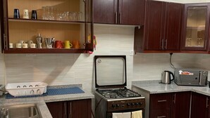 A kitchen with dark wooden cabinets, a gas stove, a sink, and a countertop with various kitchen items.