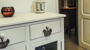 Een witte ladekast, een kleine witte lantaarn en een koperen kom erop.