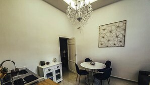 Een kleine keuken met een eethoek, een kroonluchter en een kunstwerk aan de muur.