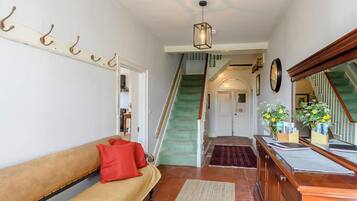 A hallway with a wooden bench, a rug, a staircase, and a mirror.